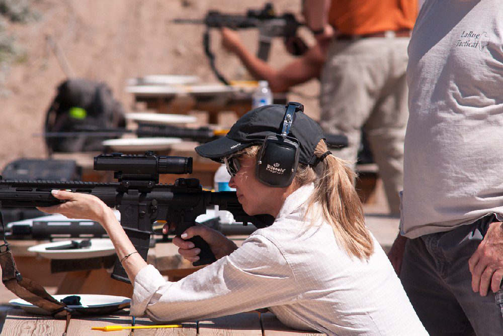 A woman is holding her gun while wearing headphones.